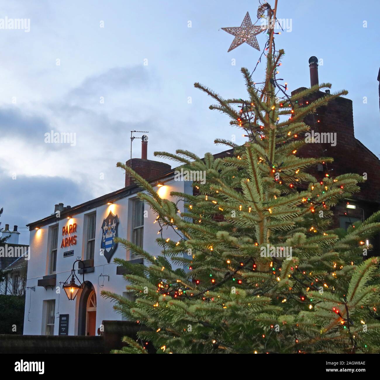 Bracci di Parr Inn e albero di Natale decorato, St Wilfrids, Chiesa Lane, Grappenhall, Warrington, Cheshire, Inghilterra al crepuscolo Foto Stock