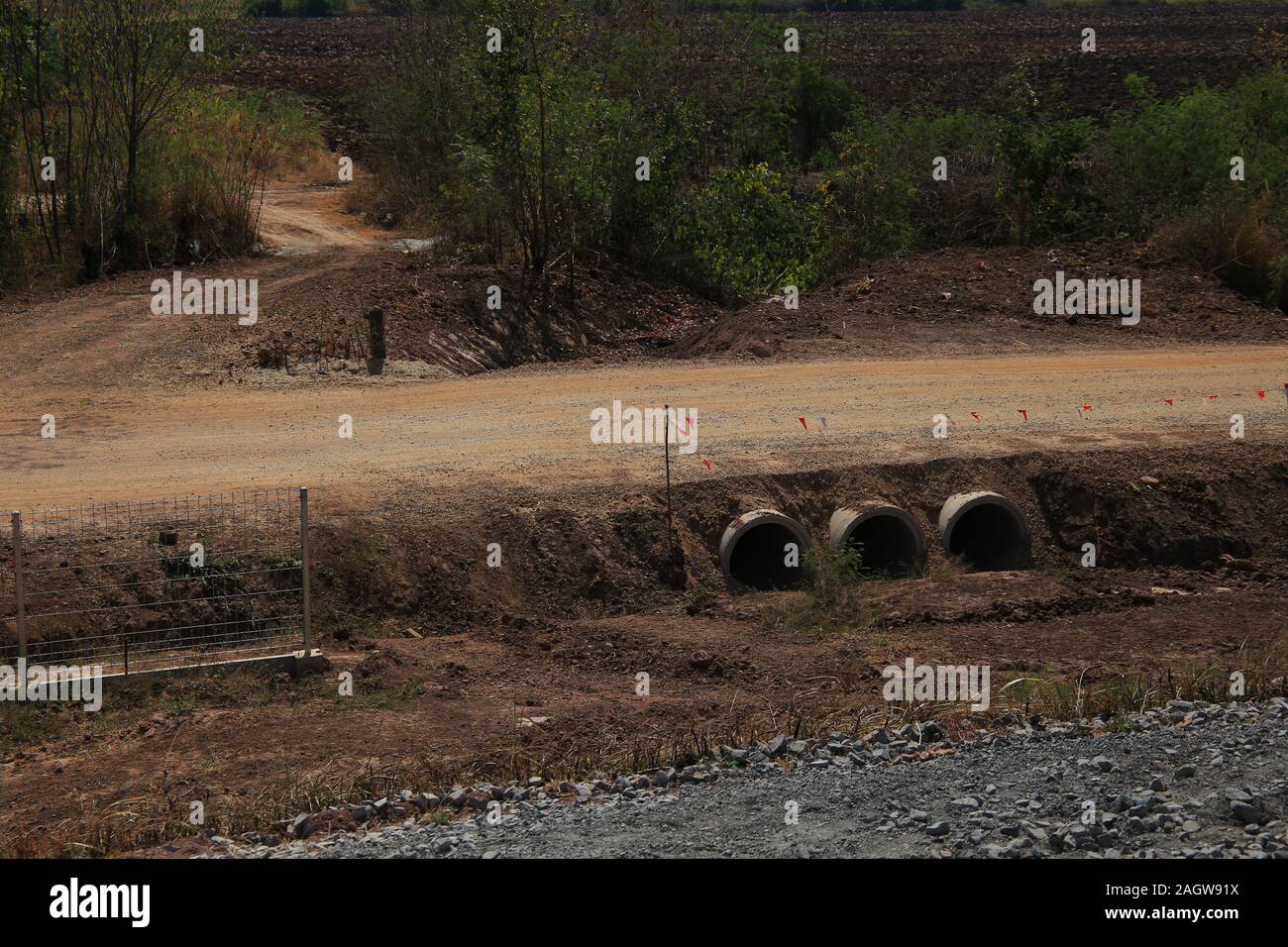 Canale sotterraneo fatto di prefabbricati in calcestruzzo tubo che va al di sotto di una compattazione del suolo di sporco in costruzione strada. ingegneria di sistema di drenaggio. ottenere acqua di inondazione da Foto Stock