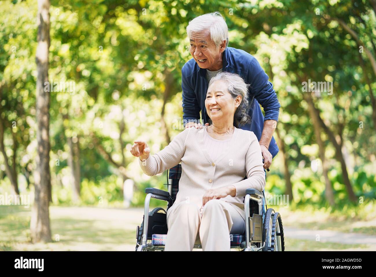 Senior uomo asiatico e sedia a rotelle donna legato di relax all'aperto nel parco Foto Stock