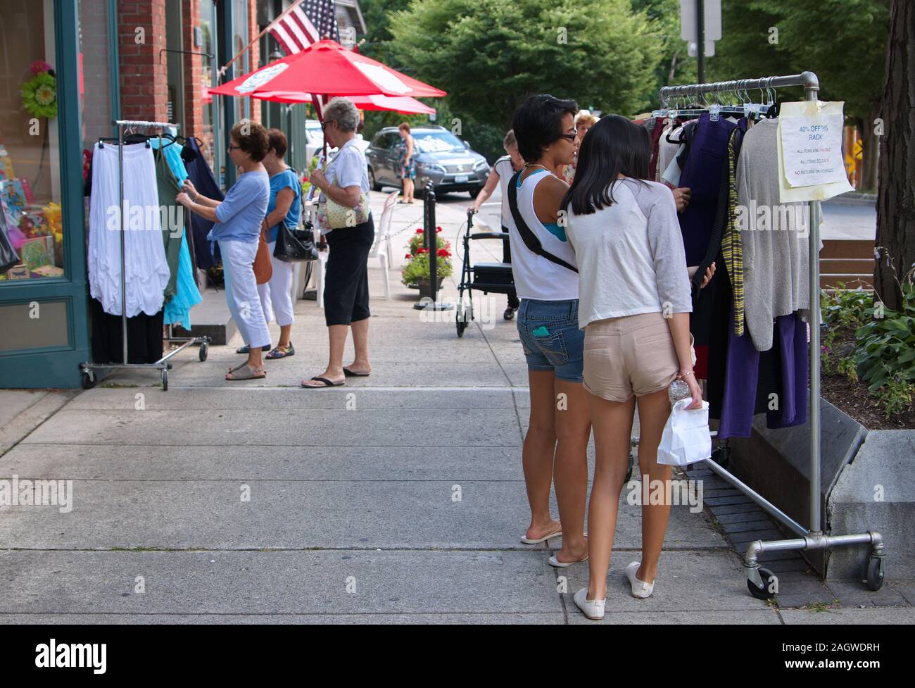 Middletown, CT, Stati Uniti d'America. Lug 2015. Americano asiatico adolescenti passando attraverso alcuni indumenti usati all'aperto presso le piccole città Main Street. Foto Stock