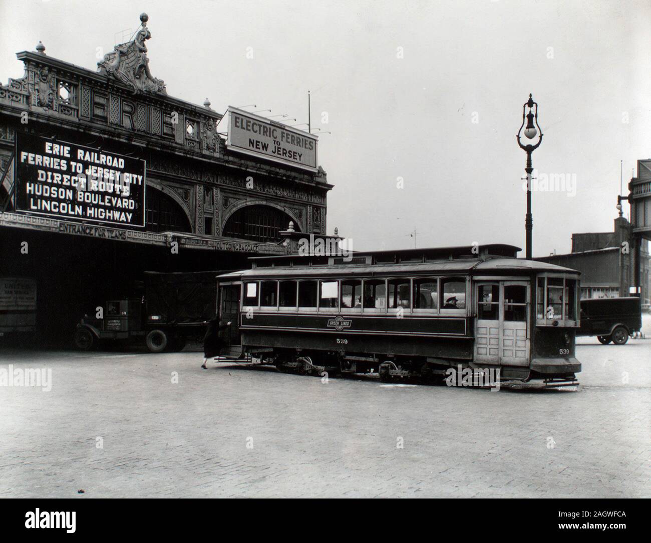 1930s New York City - schede di donna xxiii San trolley fuori Erie Railroad Ferry Terminal, West 23rd St, camion, lampione visibile. Foto Stock