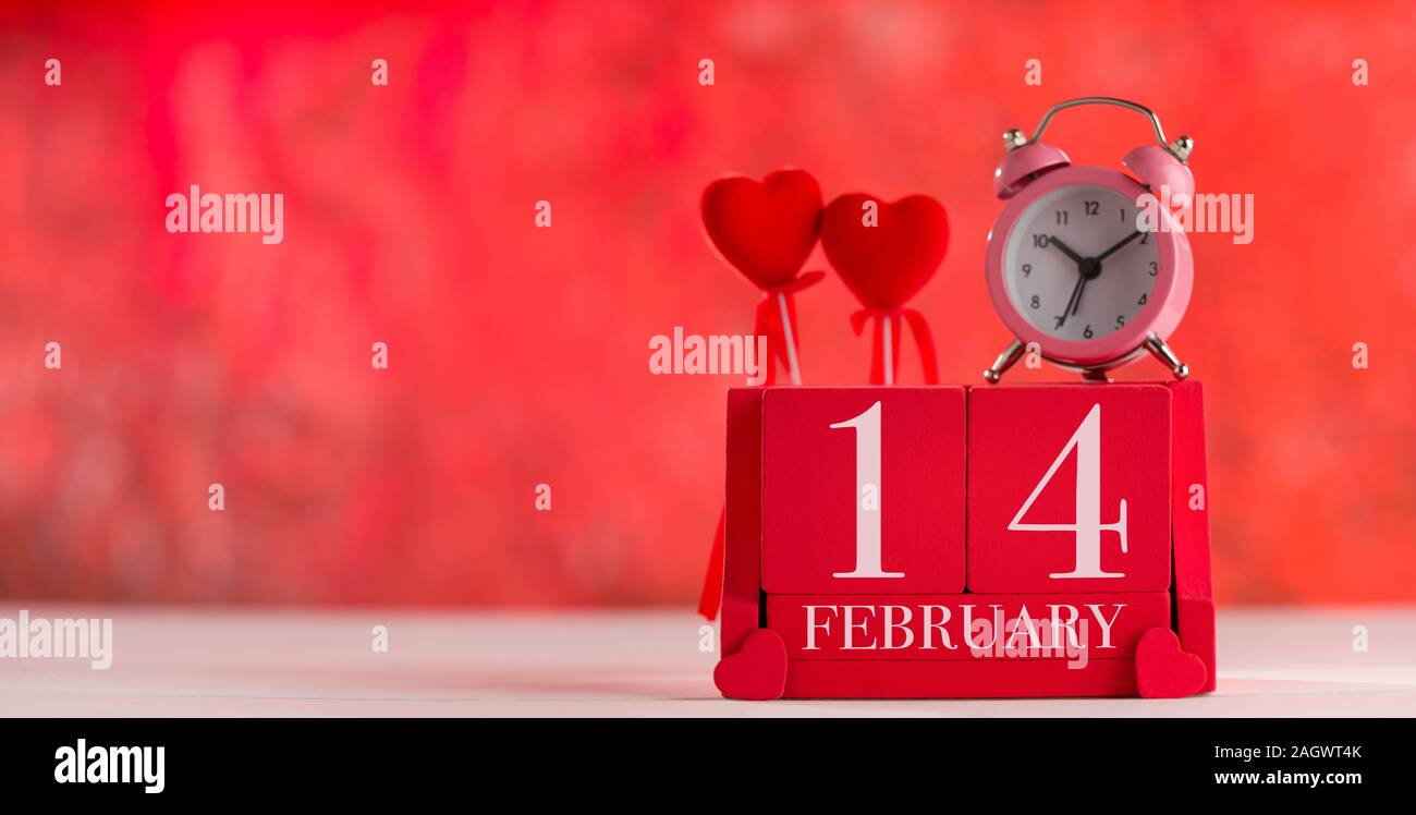 Il giorno di San Valentino del concetto. Data '' 14 febbraio '' su legno red cube calendario. Bokeh sfondo rosso Foto Stock