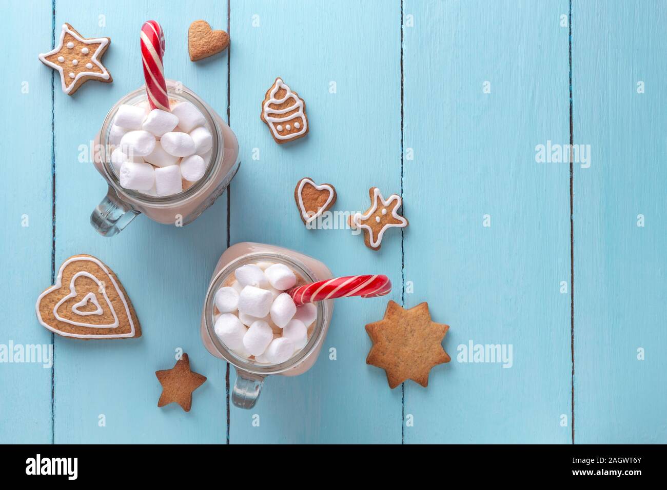 Cioccolata calda con marshmallows, una canna da zucchero e biscotti allo zenzero su uno sfondo color turchese. Vista superiore, copia dello spazio. Foto Stock