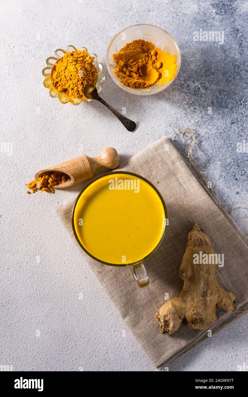 Golden curcuma latte su sfondo scuro con spezie cannella e ingredienti Foto Stock