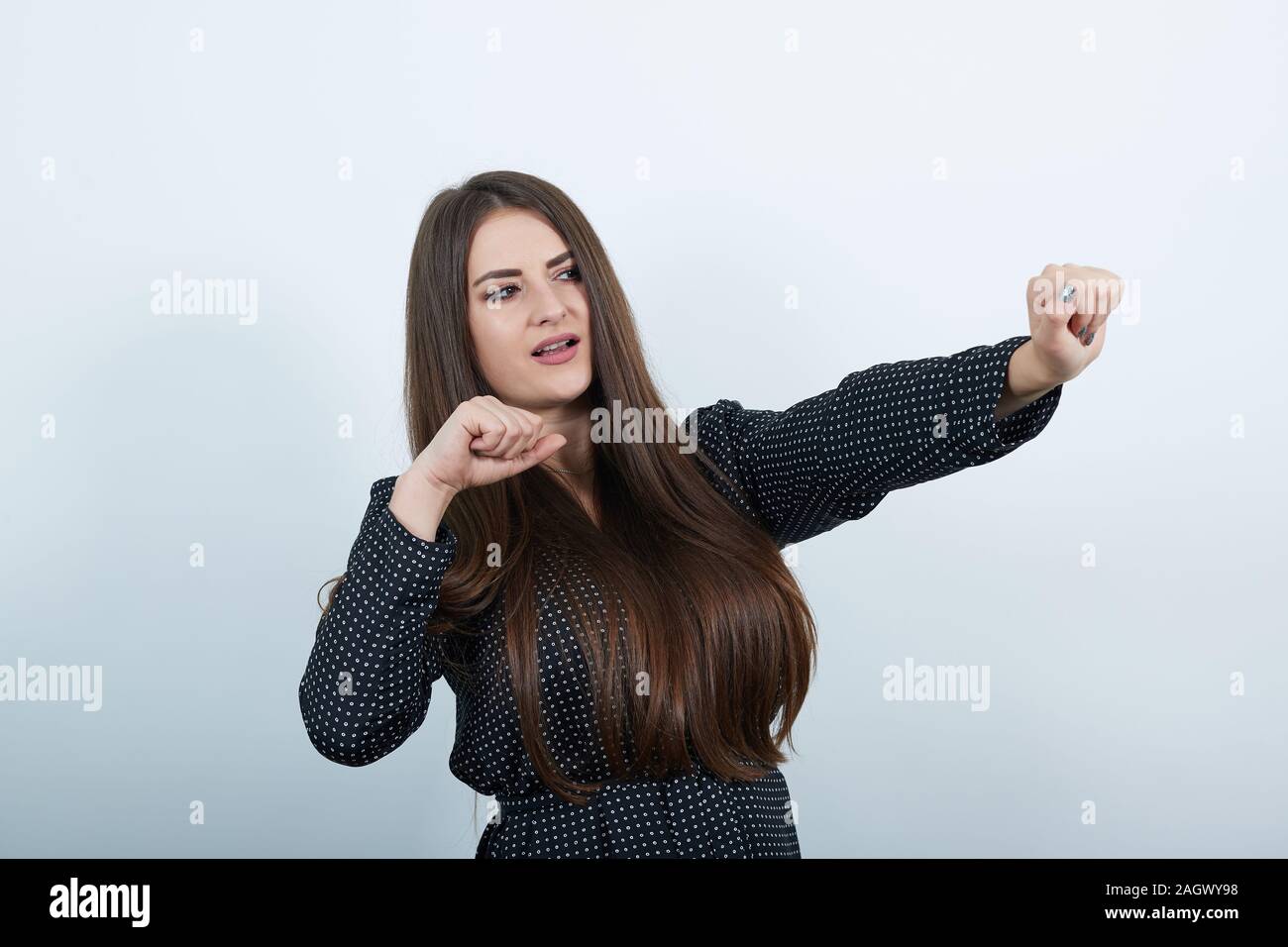 Dancing bella signora in casual abito nero con il bianco polka dot, mantenendo i pugni fino Foto Stock