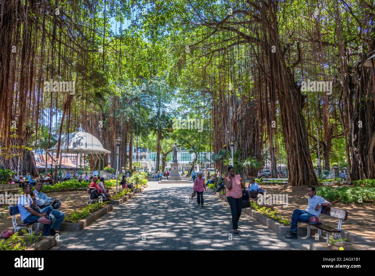 La gente camminare e seduto al Banyan Tree ombra, Port Louis Park, Mauritius Foto Stock