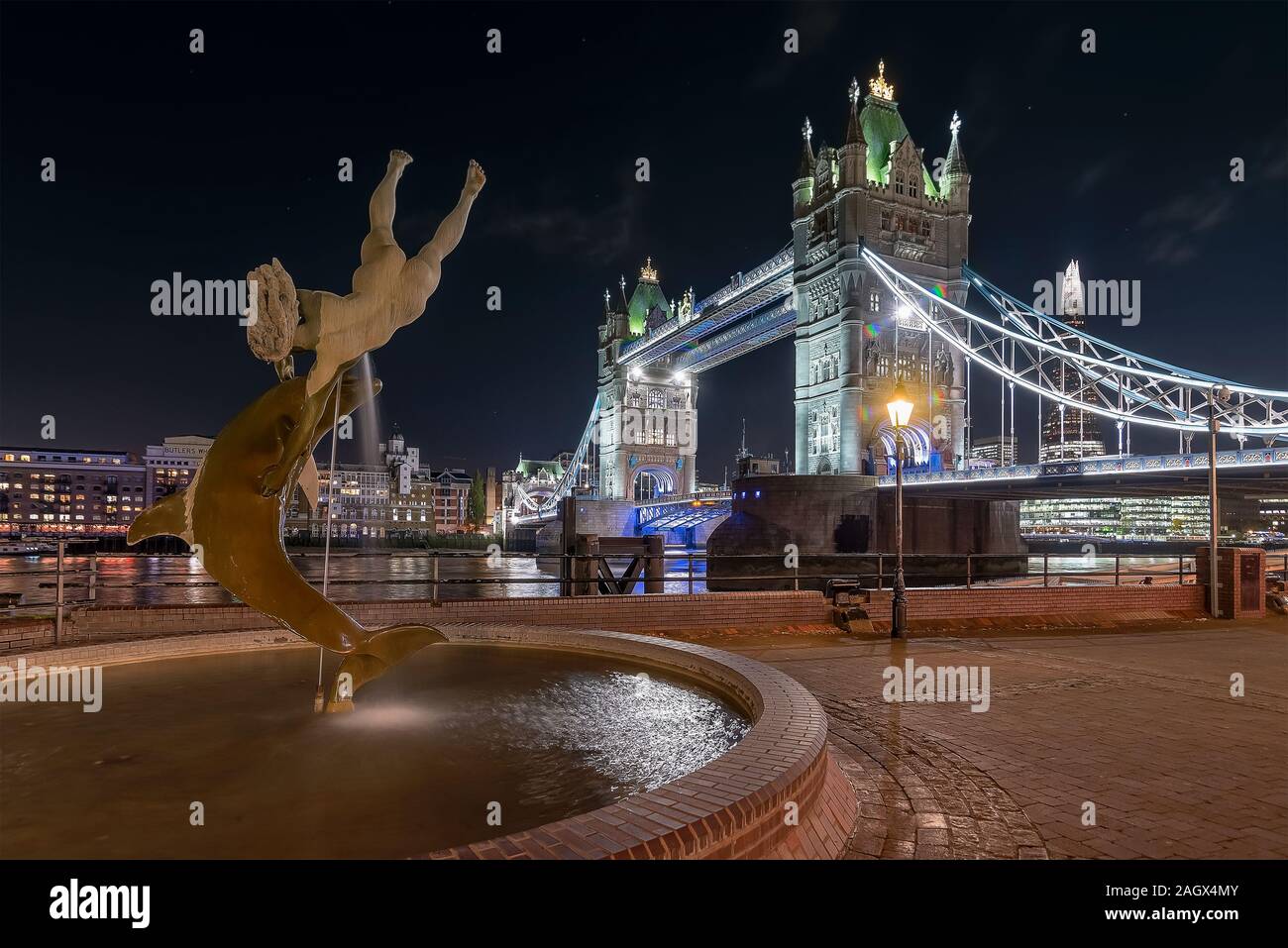 Europa, Regno Unito, Londra. Il Tower Bridge e la ragazza con una fontana dei Delfini. Paesaggio notturno Foto Stock