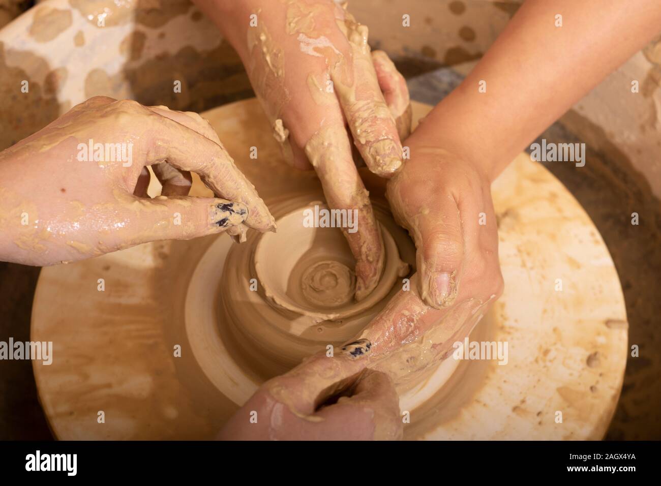 Le mani di un vasaio, creazione di un vaso di terracotta sul cerchio, vista dall'alto Foto Stock
