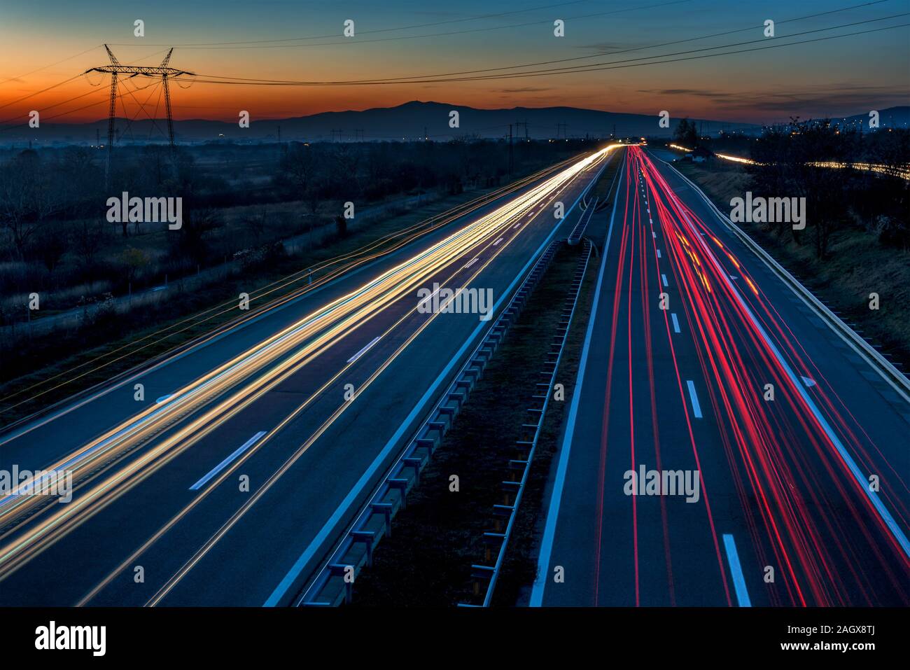 Auto sentieri di luce su una autostrada dritto al tramonto. Di notte i percorsi di traffico, motion blur, Night city road con traffico moto faro. Foto Stock