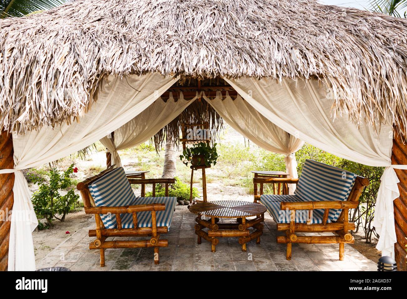 Panchine di bambù con cuscini, tavola rotonda bassa sono in un padiglione aperto paglia Foto Stock