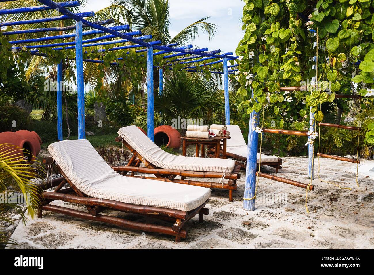 le sedie da letto di bambù, il piccolo tavolo sono sotto il tetto di legno blu in giardino Foto Stock