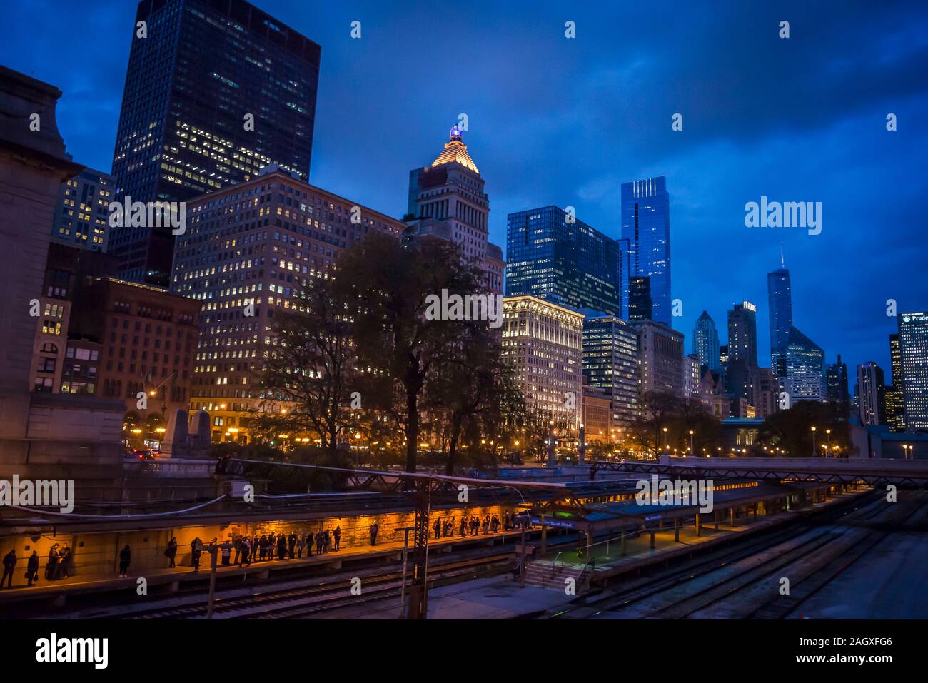 Skyline della città di grattacieli illuminati lungo South Michigan Ave, nel centro cittadino di Chicago Loop area e le linee ferroviarie e le persone in attesa di treno, Chicag Foto Stock