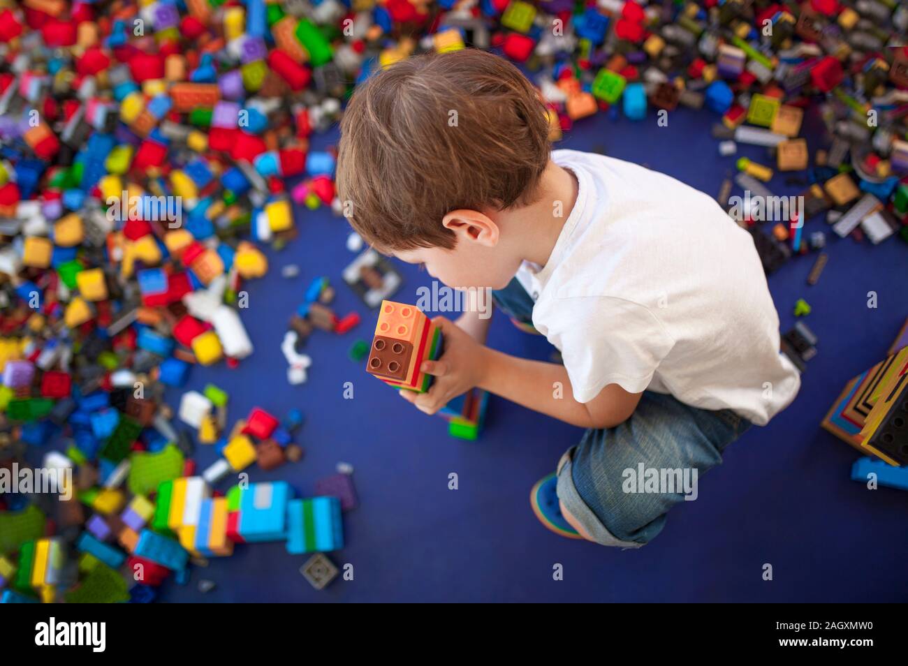 4 anni boy costruire una torre con incastro con mattoni di plastica. Messa a fuoco selettiva Foto Stock