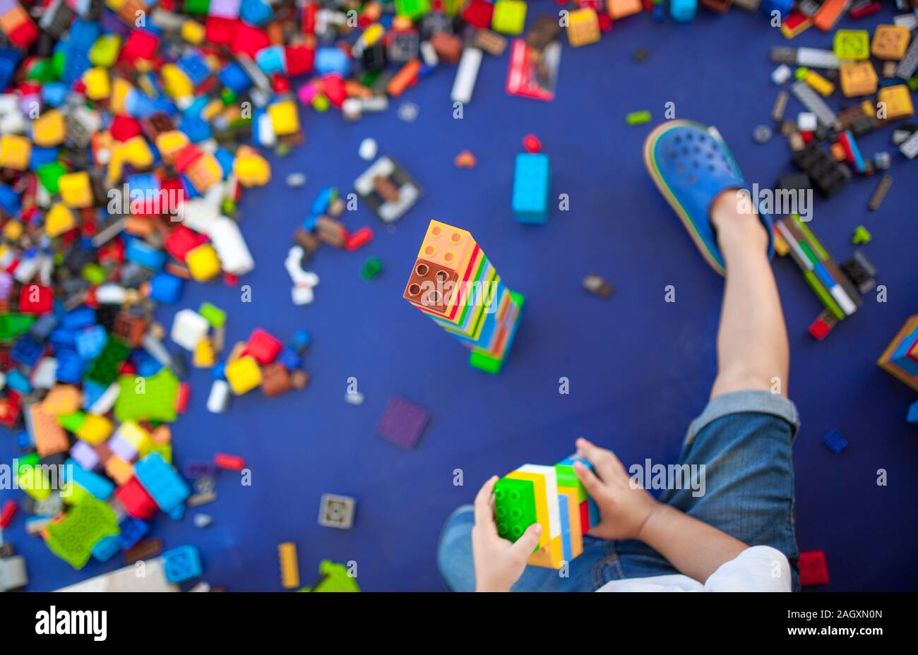 4 anni boy costruire una torre con incastro con mattoni di plastica gioco. Messa a fuoco selettiva Foto Stock