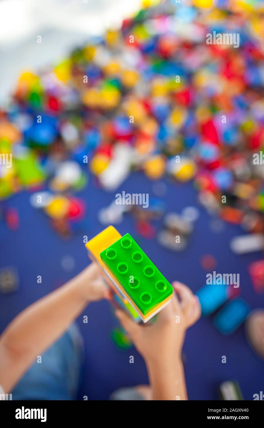 4 anni boy costruire una torre con incastro con mattoni di plastica gioco. Messa a fuoco selettiva Foto Stock