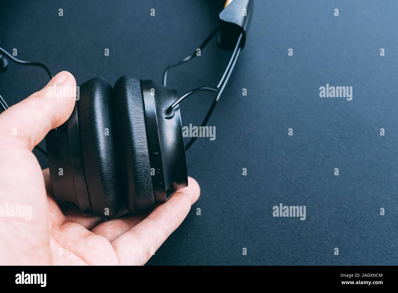 Cuffia wireless è attesa o appeso a un man mano sinistra con sfondo nero e copiare lo spazio per testo Foto Stock
