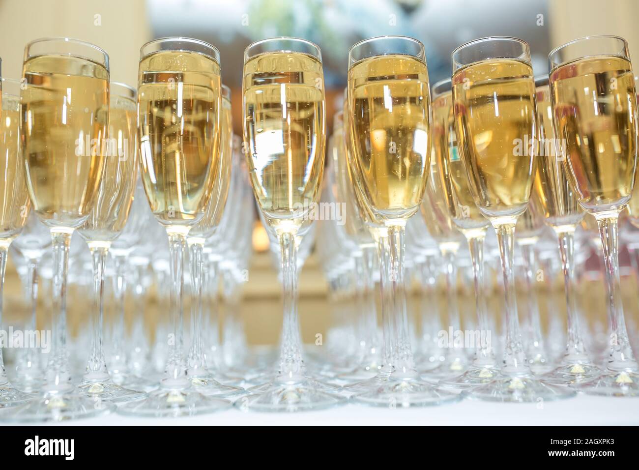 Sacco di offuscata occhiali con champagne sulla ricezione delle parti tabella su sfondo chiaro Foto Stock