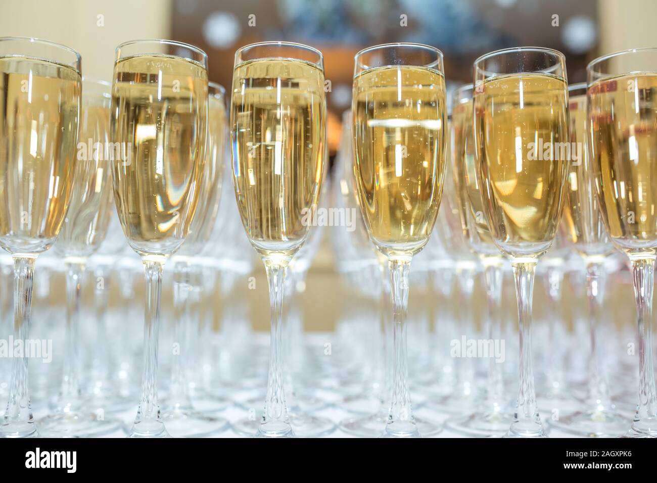 Sacco di offuscata occhiali con champagne sulla ricezione delle parti tabella su sfondo chiaro Foto Stock