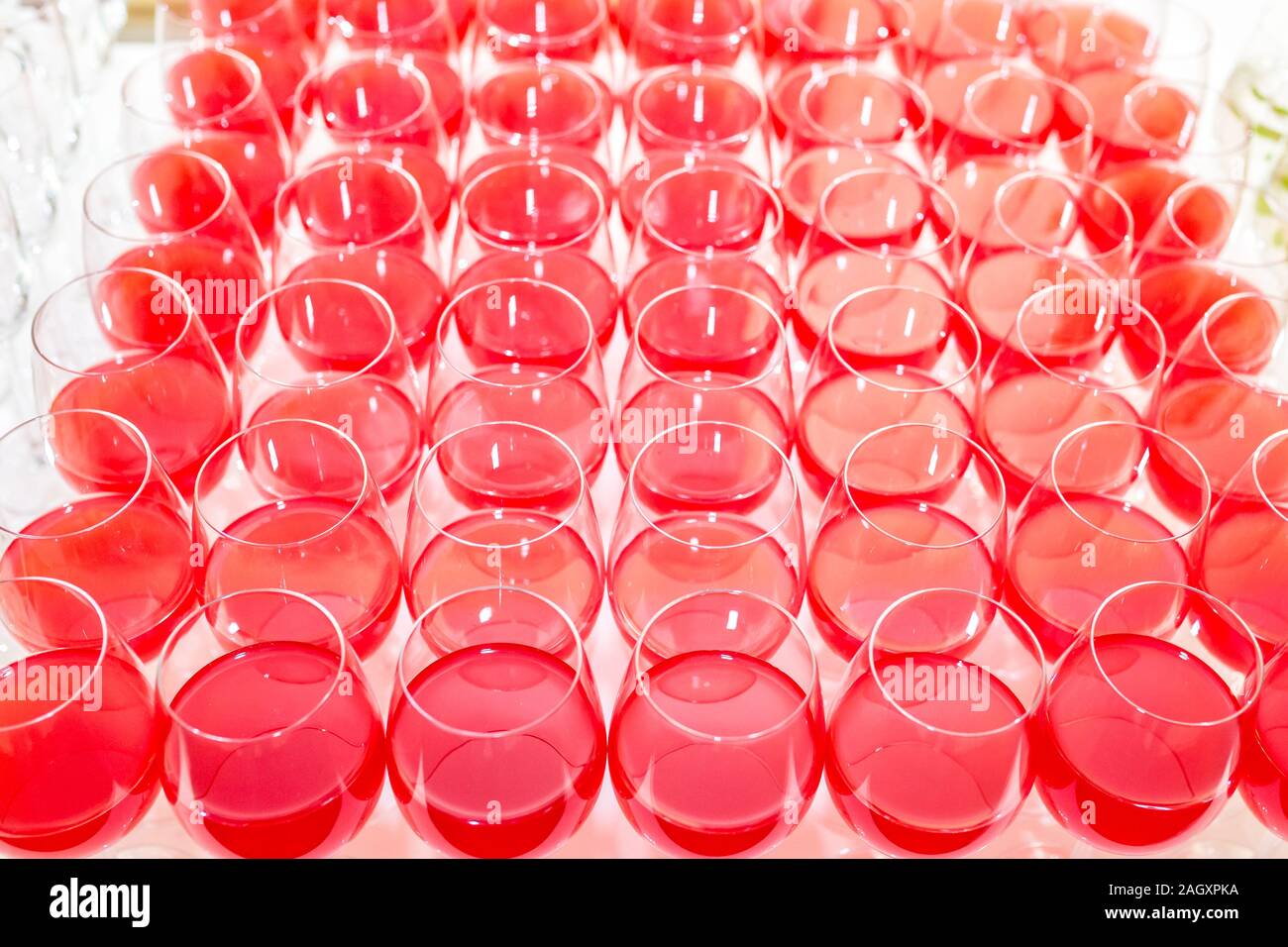 Sacco di offuscata bicchieri da vino rosso sulla parte di ricezione tabella su sfondo chiaro Foto Stock