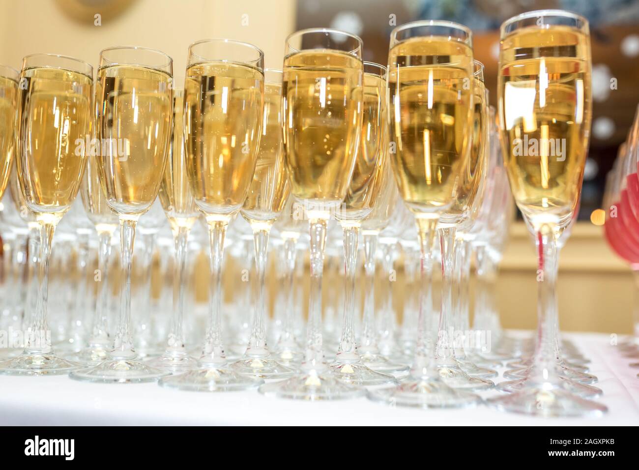 Sacco di offuscata occhiali con champagne sulla ricezione delle parti tabella su sfondo chiaro Foto Stock