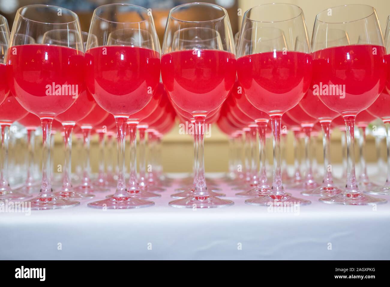 Sacco di offuscata bicchieri da vino rosso sulla parte di ricezione tabella su sfondo chiaro Foto Stock