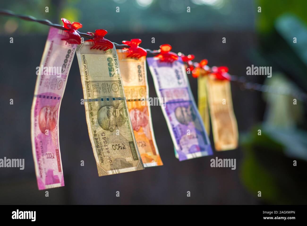 Messa a fuoco selettiva di nuovo la valuta indiana constata rupie dieci,venti,cinquanta cent,duecento,cinquecento e due mila appeso a un filo. Foto Stock