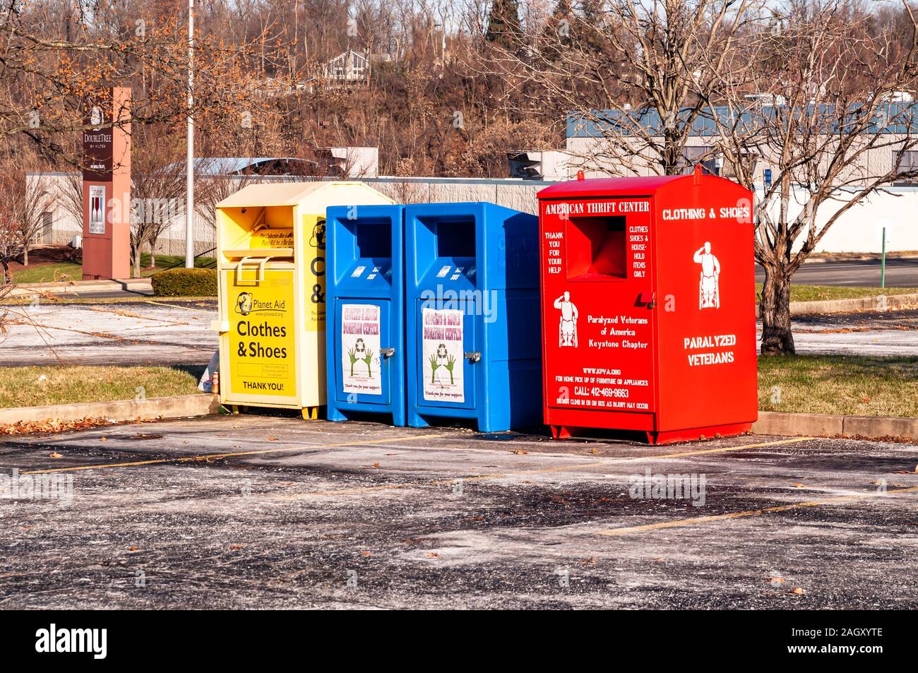 Abiti da quattro scatole di raccolta di diversi colori, uno giallo e uno rosso e due blu in un parcheggio, Monroeville, Pennsylvania, STATI UNITI D'AMERICA Foto Stock
