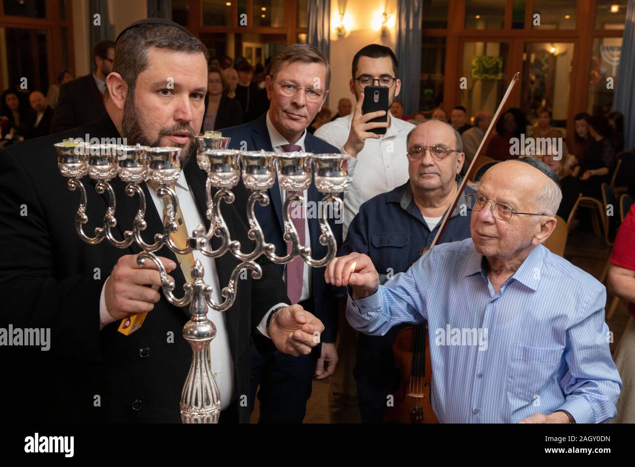 Bremen, Germania. 22 Dic, 2019. Rabbi Natanel Teitelbaum (l) accende un cero Hanukkah insieme con superstite dell' Olocausto Grigori Skoblov (90) all'Hanukkah celebrazione nella Comunità Ebraica centro a Brema in occasione del 'International superstiti notte' del popolo ebraico rivendicazioni da conferenza. La cerimonia in onore dei sopravvissuti all Olocausto avrà luogo anche a Monaco di Baviera, New York, Mosca, Parigi e Gerusalemme. Credito: Jörg Sarbach/dpa/Alamy Live News Foto Stock