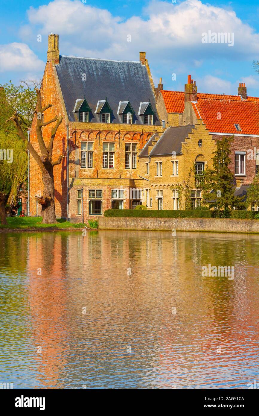 Bruges, Belgio Minnewater lago dell'amore e case medievali contro nuvoloso cielo blu Foto Stock