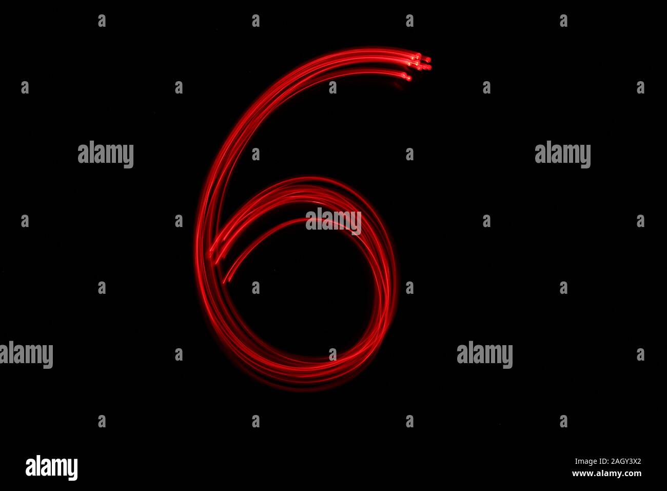La pittura di luce fotografia di un numero, disegnato da luci fairy in rosso vivace Colore del neon contro uno sfondo nero. Fotografie con lunghi tempi di esposizione. Foto Stock