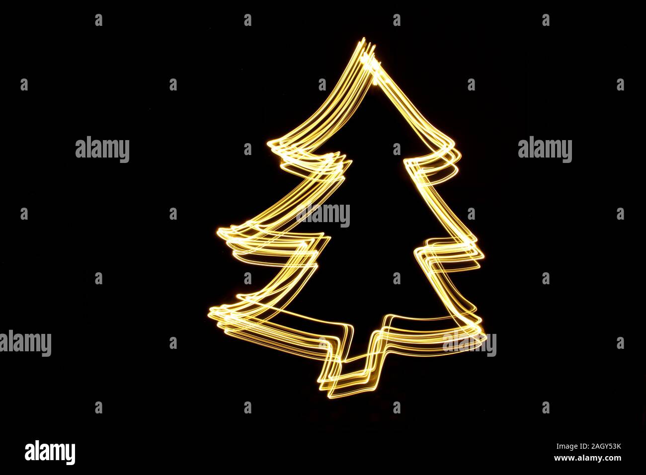 La pittura di luce fotografia di un festoso albero di Natale contorno, neon vibrante colore oro su sfondo nero. Fotografie con lunghi tempi di esposizione. Foto Stock