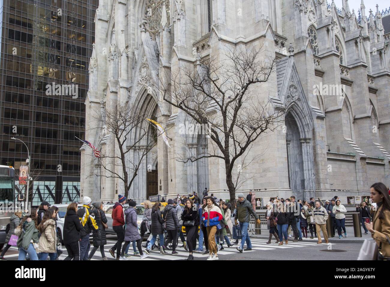 Una folla di persone attraversano la Quinta Avenue sulla 50a Strada al Rockefeller Center con Saint Patrick in background. Foto Stock