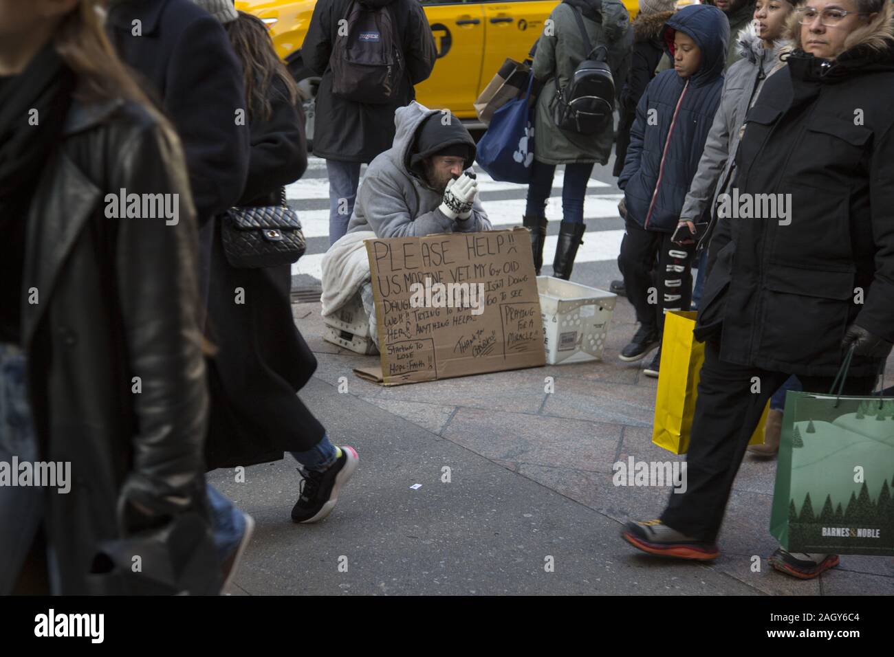 Sconsolato senzatetto US marina il veterano raggiunge fuori come acquirenti e turisti passano lungo la Quinta Avenue nel centro di Manhattan su 'Venerdì Nero" Foto Stock