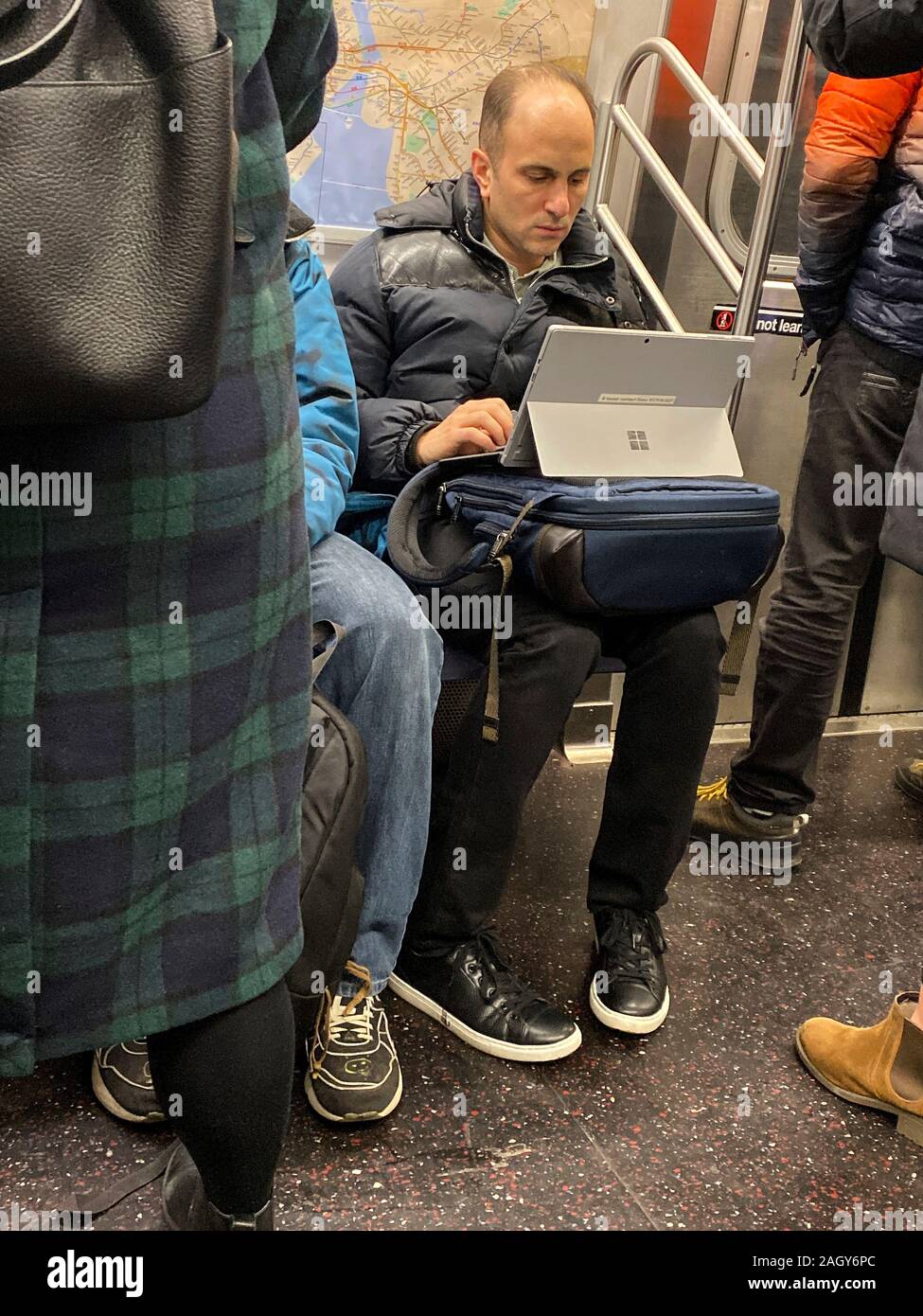 L'uomo già al lavoro sul suo modo di lavorare su una metropolitana di New York il treno. Foto Stock