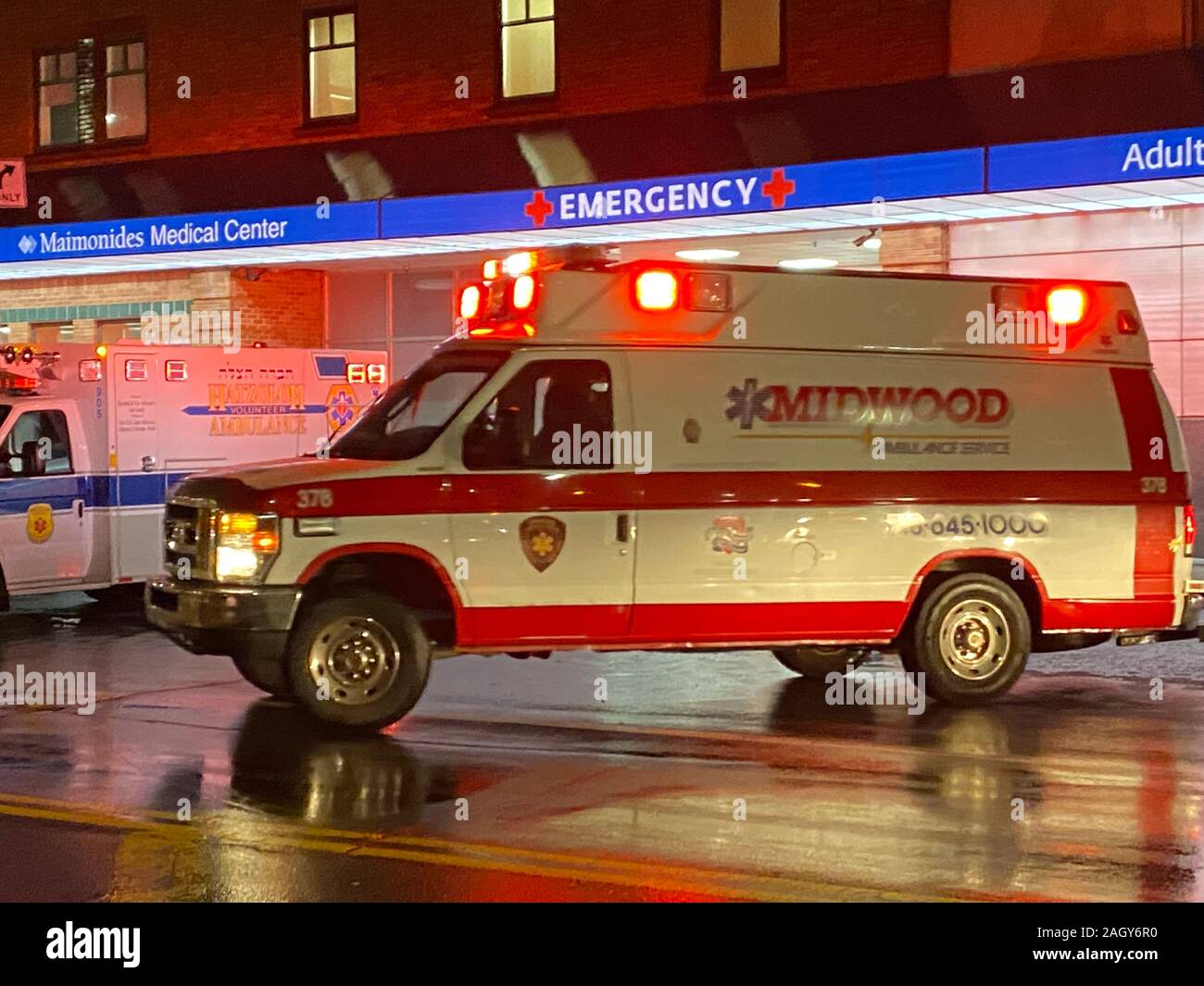 Ambulanza tirando fuori da Maimonides Medical Center di emergenza area di parcheggio di emergenza eseguito su un autunno piovoso notte a Brooklyn, New York. Foto Stock