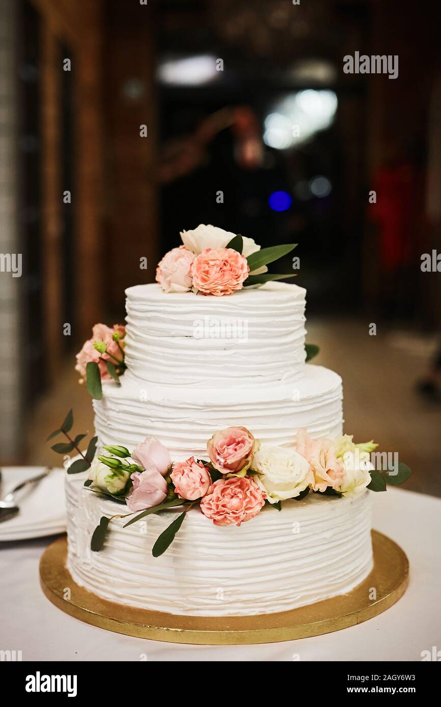 Bianco torta di nozze con fiori rosa e bianchi di peonie e rose. Extra large su tre livelli, torta di nozze con bianco di glassa di crema di burro e fresco Foto Stock