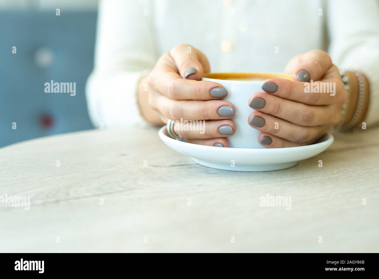 Le mani della giovane donna riposante in informale holding tazza di caffè Foto Stock