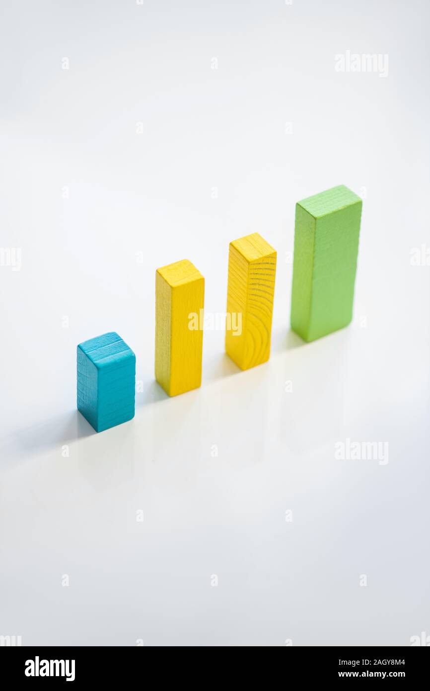 Fila di blu, giallo e verde piana mattoni di legno che compongono il grafico finanziario Foto Stock