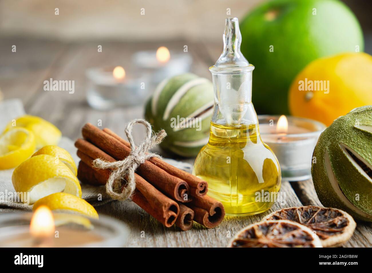 Bottiglia di agrumi Olio essenziale di limone per aromaterapia, agrumi, bastoncini di cannella e candele accese. Foto Stock