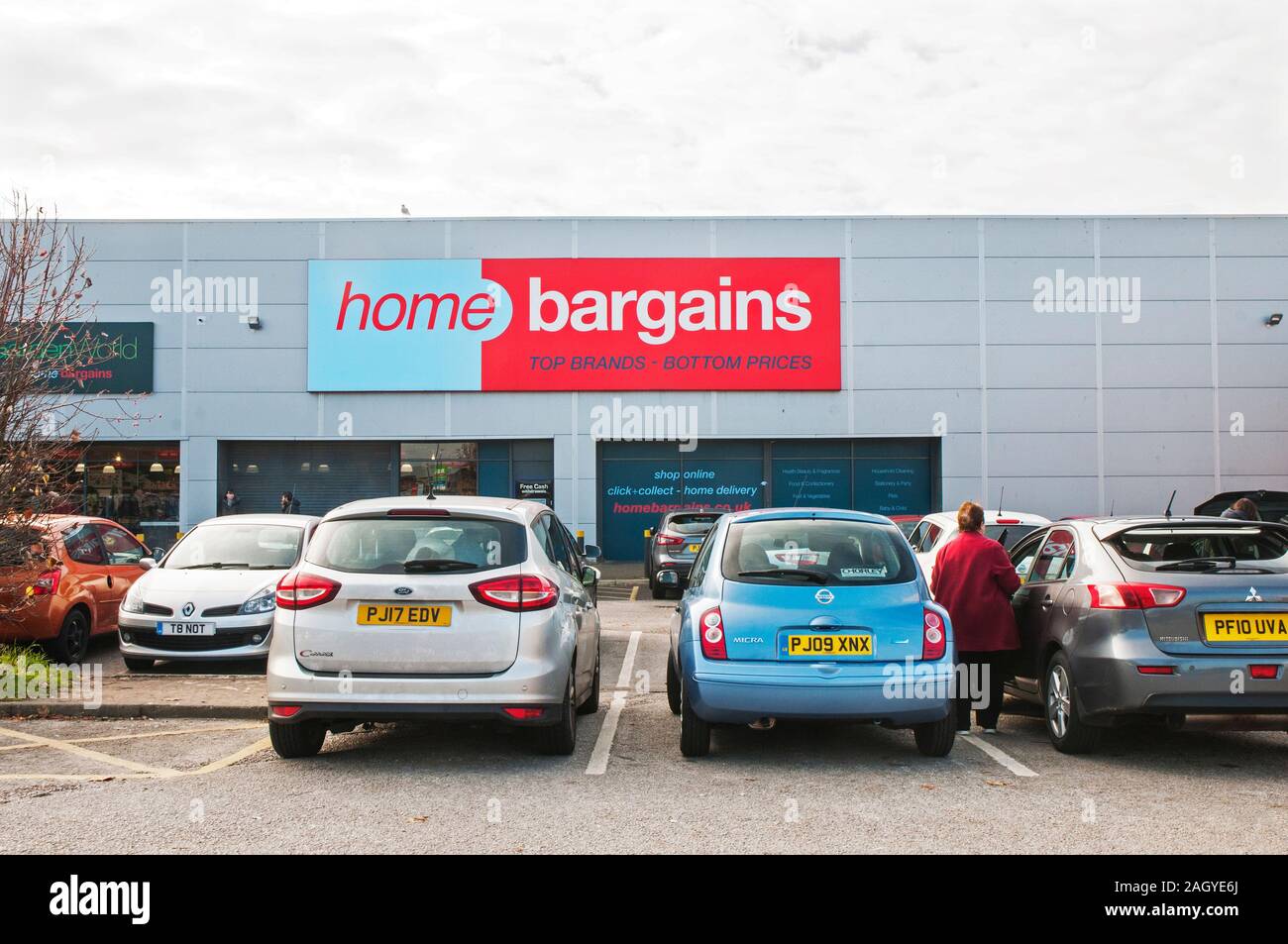 Gli acquirenti di automobili parcheggiate sul parcheggio a casa occasioni store. Foto Stock