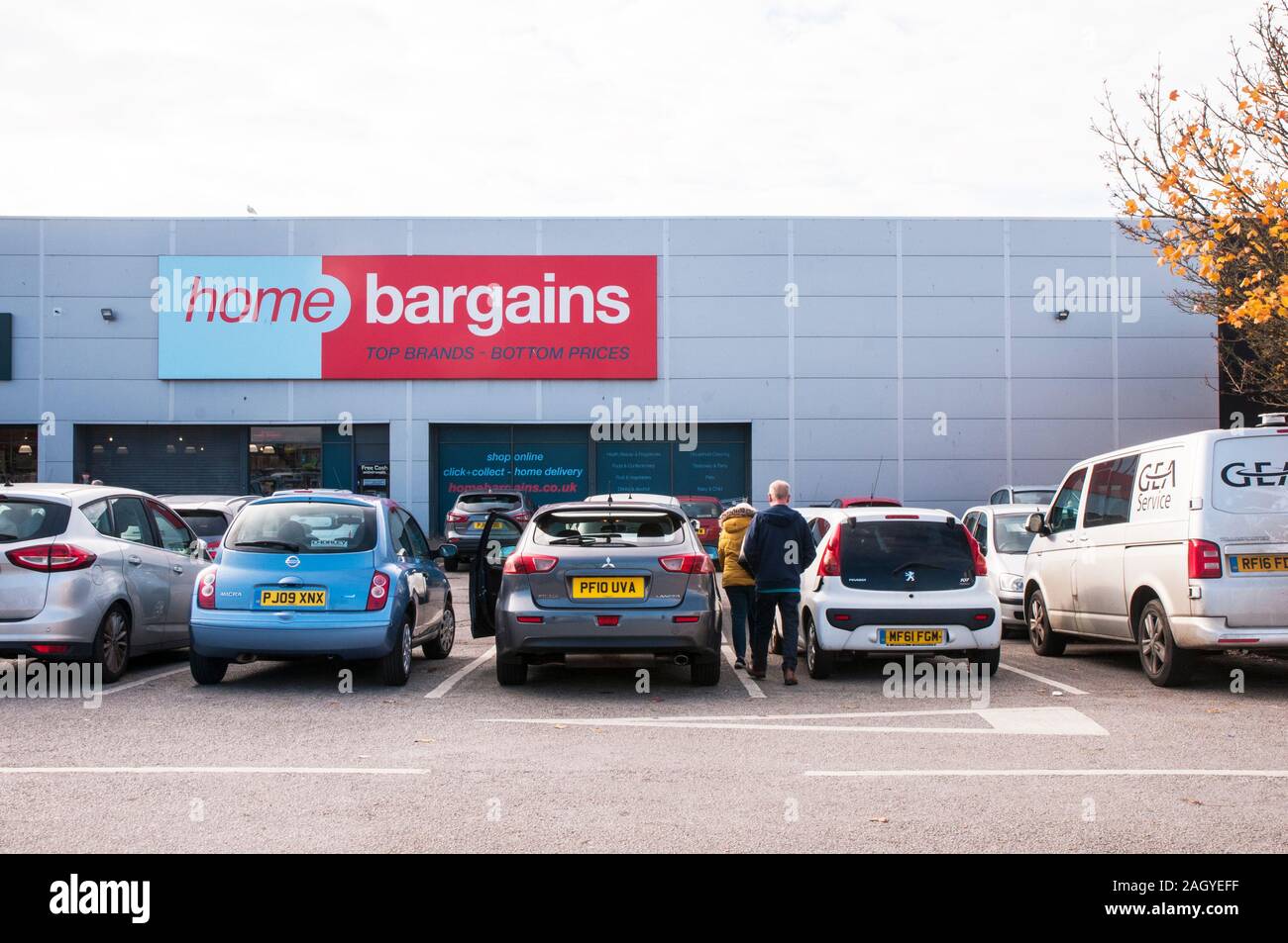 Gli acquirenti di automobili parcheggiate sul parcheggio a casa occasioni store. Foto Stock