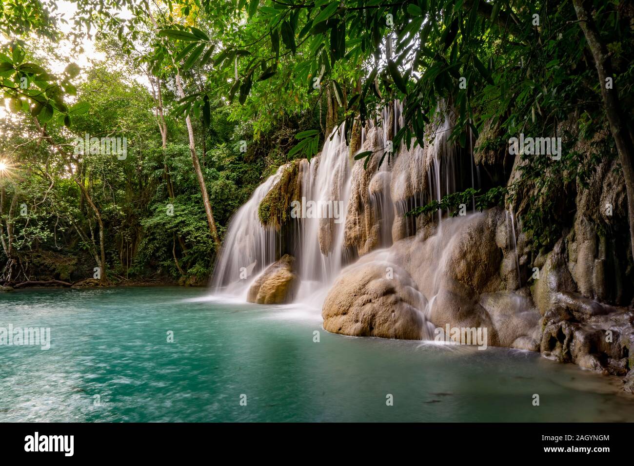 Pulite acque verde smeraldo dalla cascata circondata da alberi piccoli - grandi alberi, colore verde, Erawan cascata, la provincia di Kanchanaburi, Thailandia Foto Stock