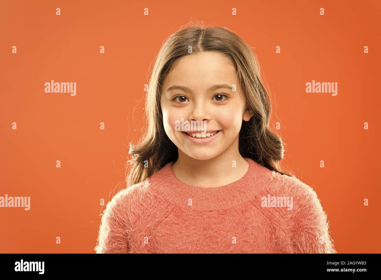 Cura del viso. La cosmetologia concetto di bellezza. Bambine viso carino sfondo arancione. Infanzia felice. Prodotti per la cura del bambino e psicologia. Il benessere e la salute. La felicità radiante. Bambini sorridenti vicino. Foto Stock