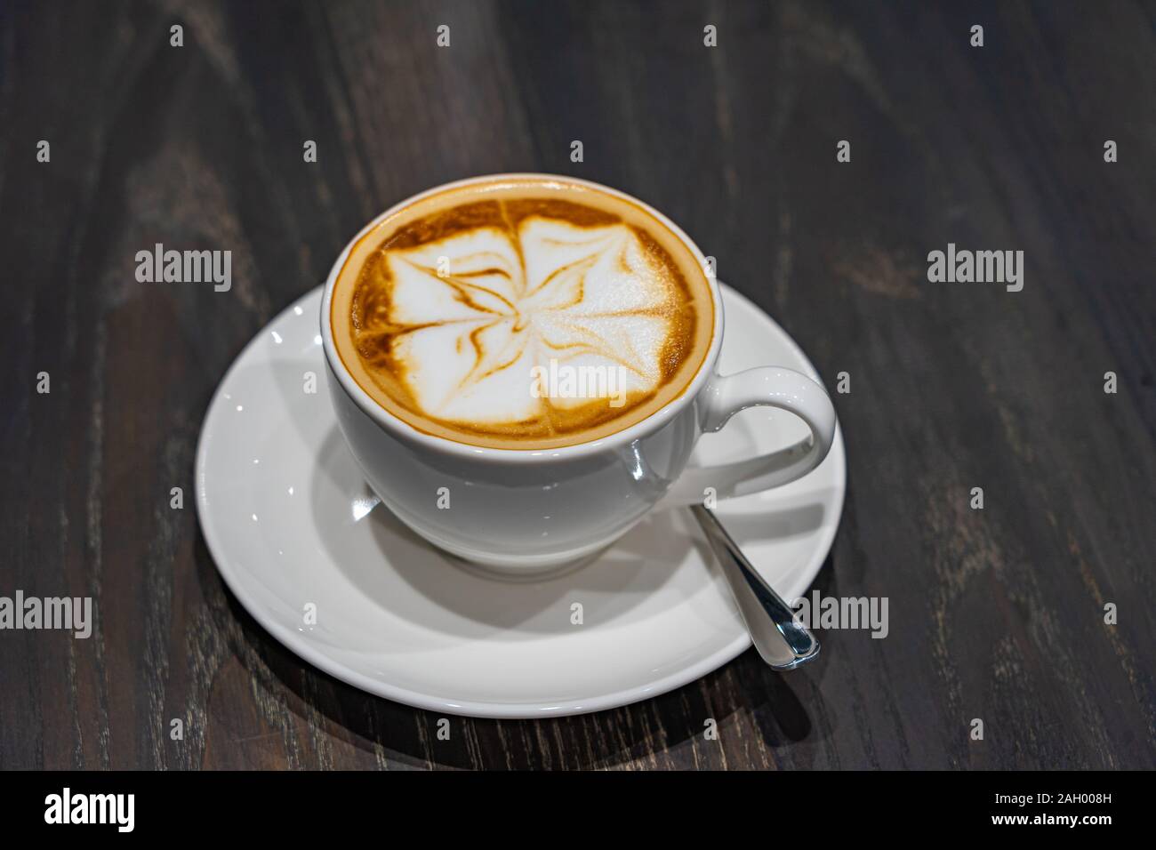 Latte art caffè con grazioso motivo floreale schiuma di latte Foto Stock