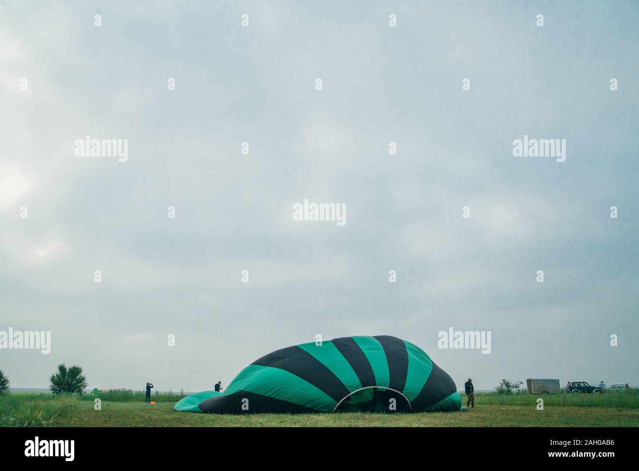 Il gonfiaggio, disimballare e volare fino in mongolfiera ad aria calda di anguria. Bruciatore dirigere la fiamma in busta. Togliere gli aerei volano al mattino cielo blu. Foto Stock