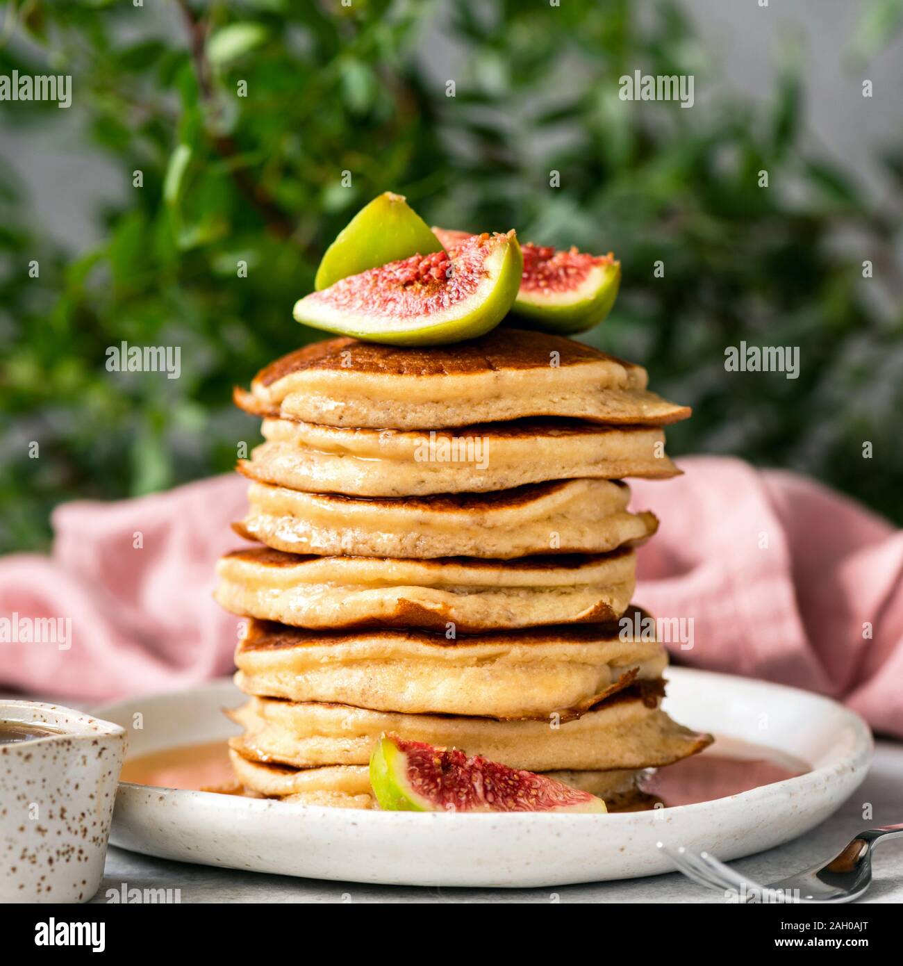 Pila di deliziose frittelle soffici e rabboccato con fichi freschi e sciroppo d'acero. Orientamento quadrati. Colazione dolce alimenti ricchi in carboidrati e glutine Foto Stock
