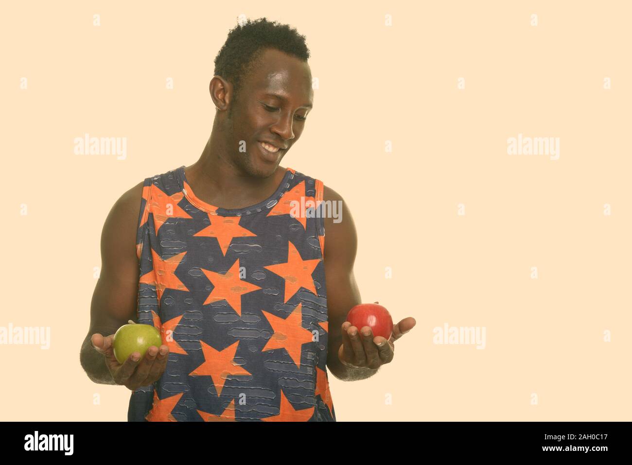 Giovani felici Africano nero uomo sorridente e scegliendo tra il verde e il rosso apple Foto Stock