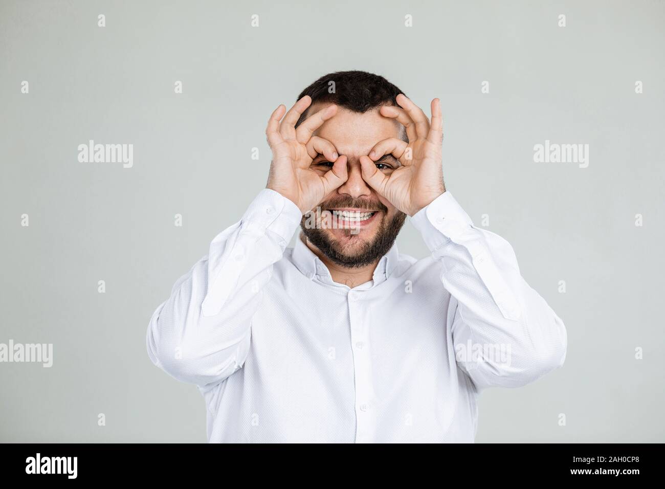 Ritratto di divertenti uomo barbuto ingannare circa su sfondo grigio. Foto Stock