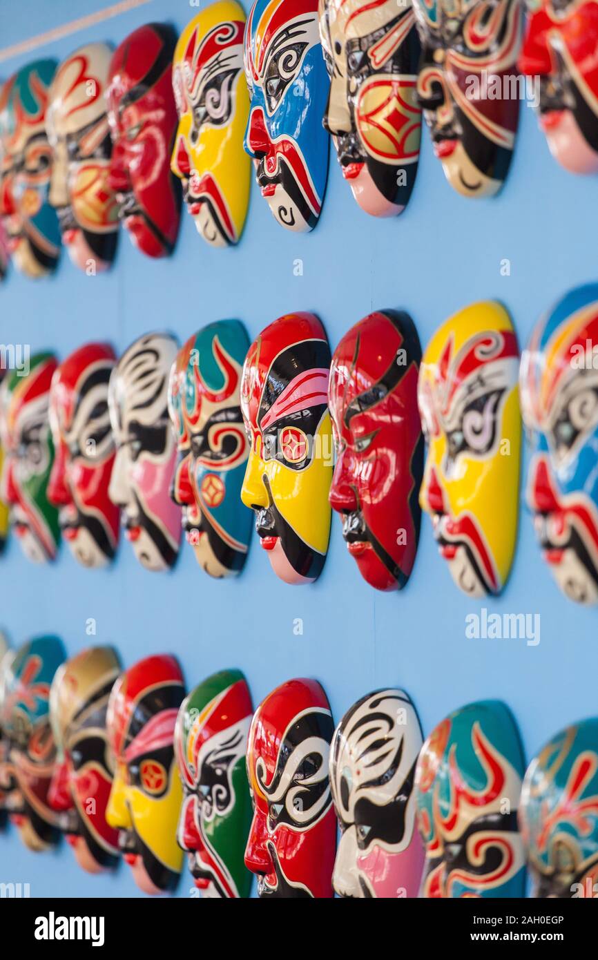 Colorato dipinto a mano opera cinese maschere riagganciare ordinatamente su una parete di blu. I vari colori ciascuna maschera rappresenta diverse caratteristiche. Foto Stock