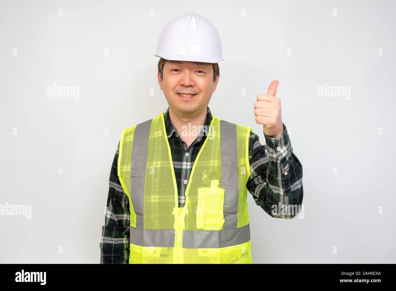 Asian uomo di mezza età in una luce verde giubbotto di lavoro e di sicurezza bianca cappello. Foto Stock